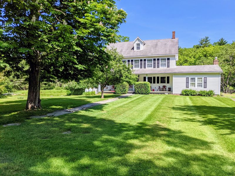 Striped lawn in front of a white farmhouse
