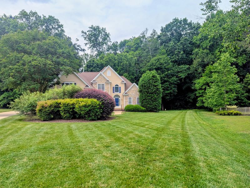 Striped front lawn leading up to a house with trimmed shrubs